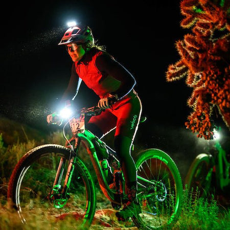Mountain biker riding at night with a Trail Evo handlebar light and Hangover helmet light switched on
