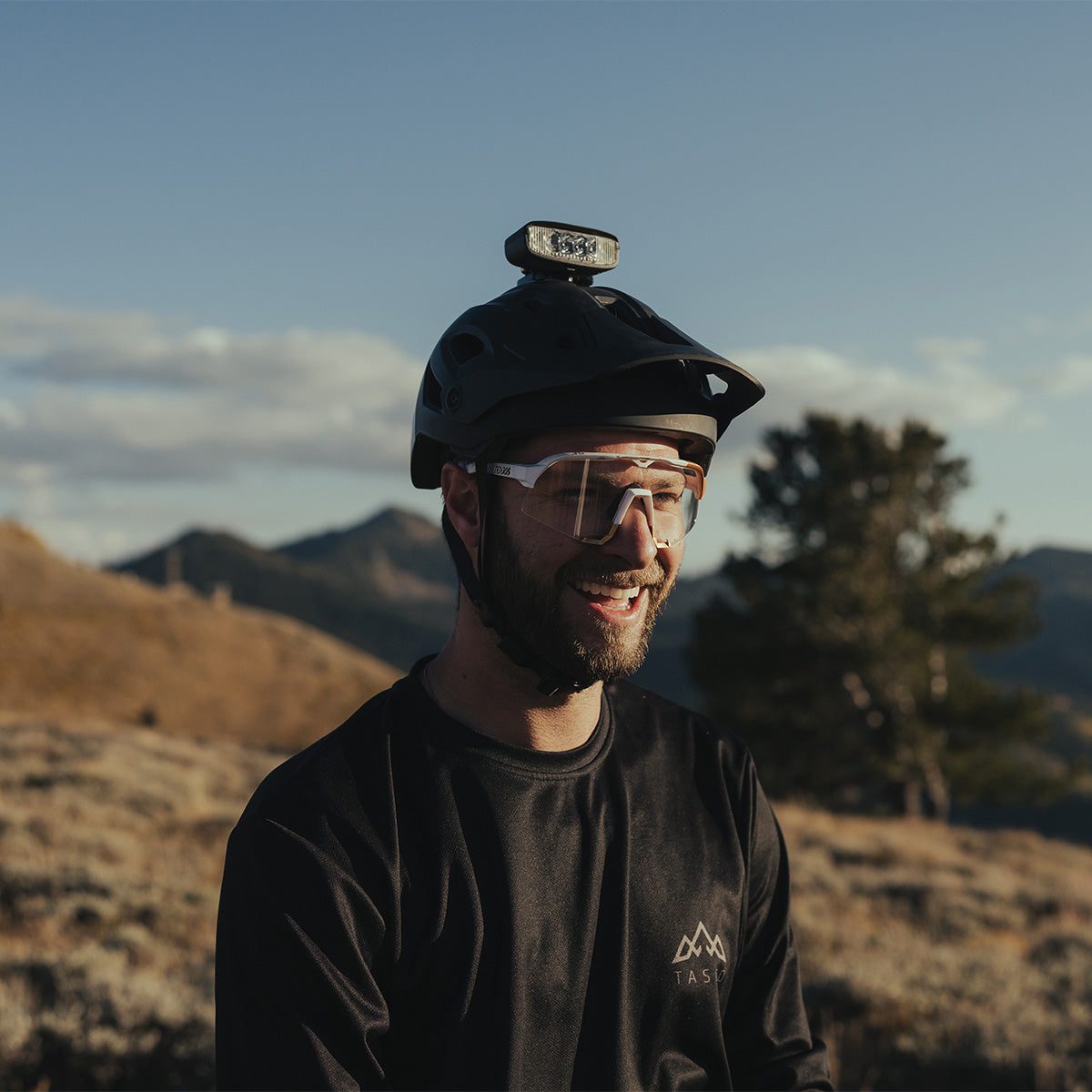 Rider at dusk wearing a mountain bike helmet with the Hangover helmet light mounted on top