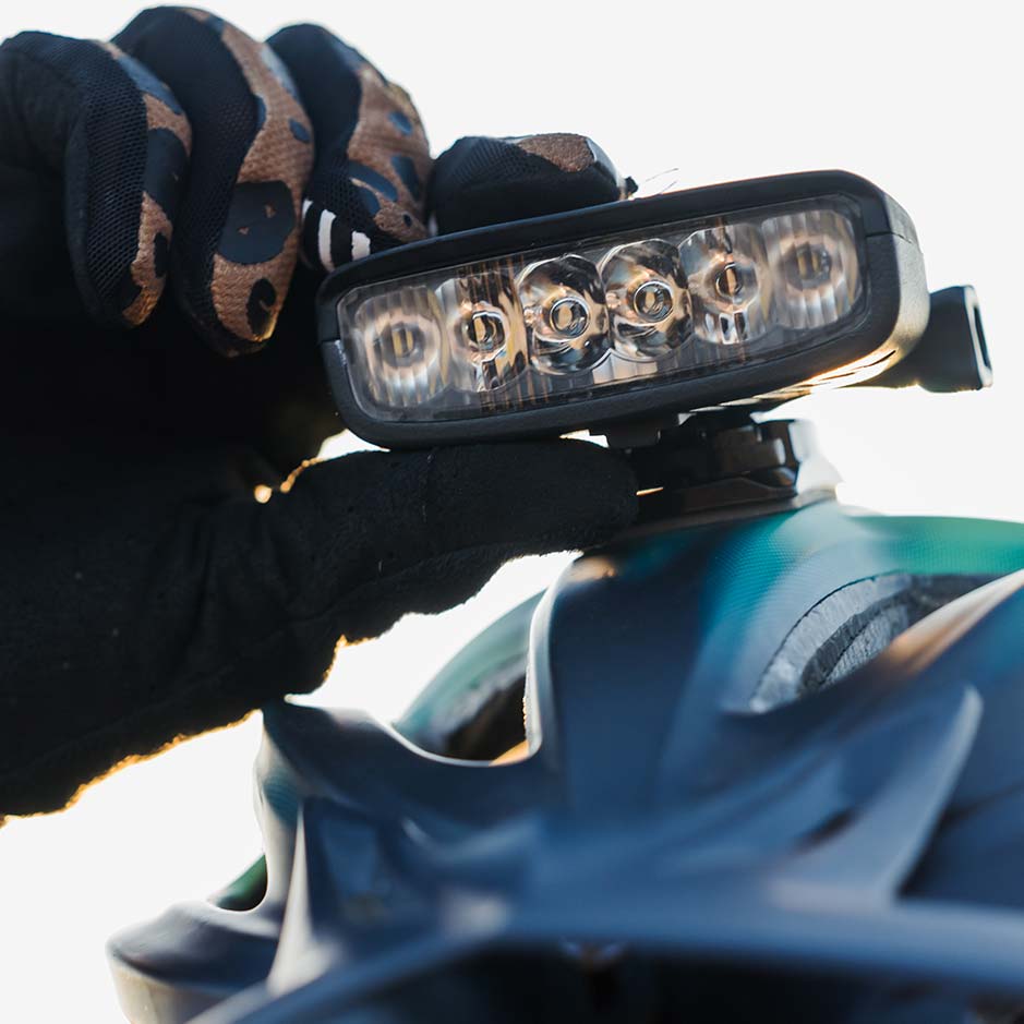 Gloved hand pressing the button on a Hangover bike helmet light mounted on a helmet