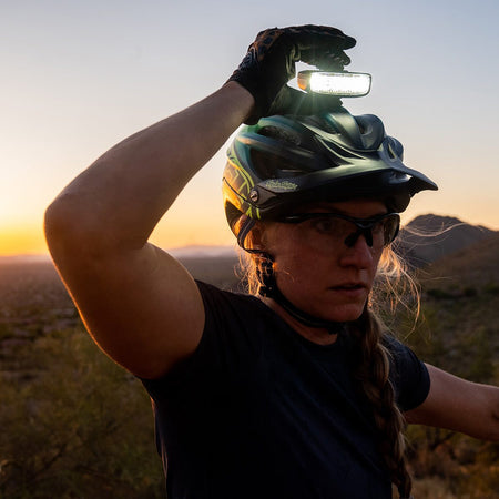 Rider reaching up to switch on the Hangover bike helmet light at sunset