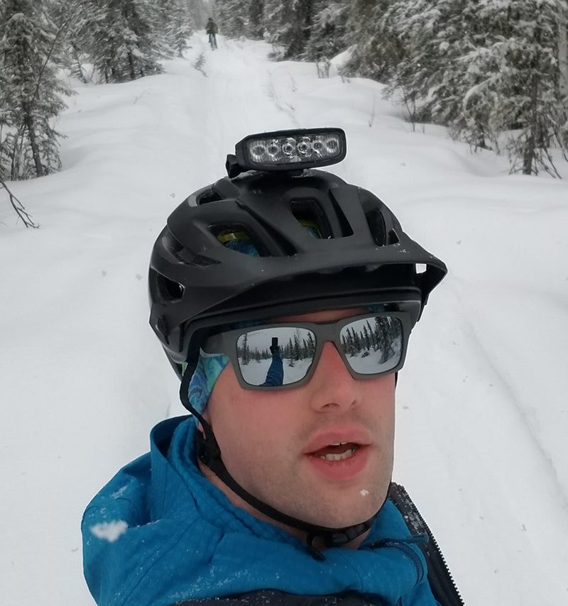 Rider on a snowy trail wearing a helmet with the Hangover bike helmet light mounted on top