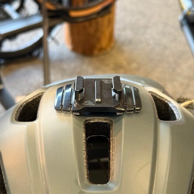 Close-up of the wide helmet mount bridging the center vent of a tan bike helmet