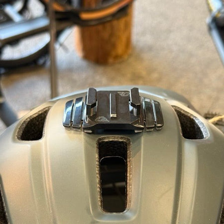 Close-up of the wide helmet mount bridging the center vent of a tan bike helmet
